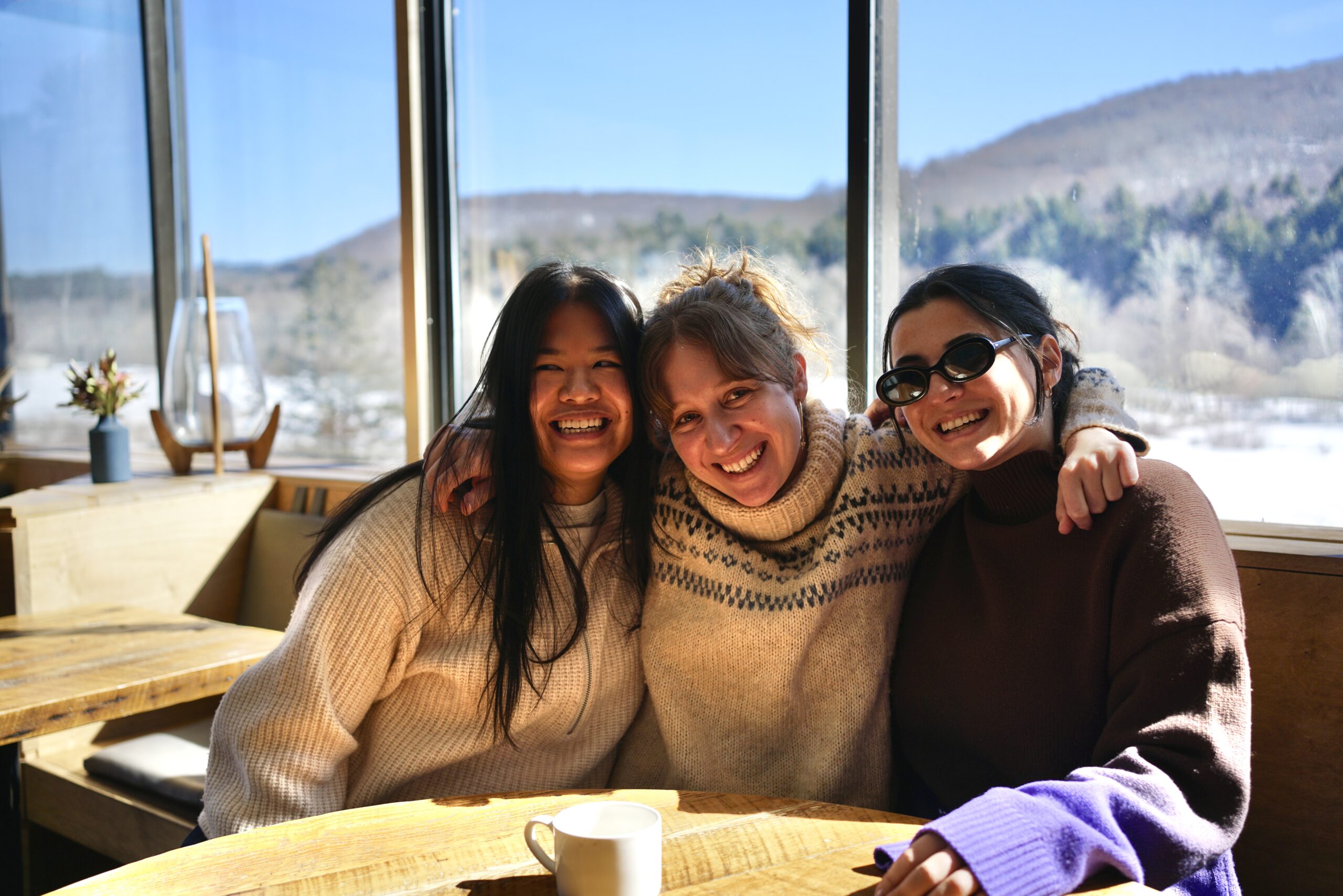 Three women smile at a table at The DeBruce