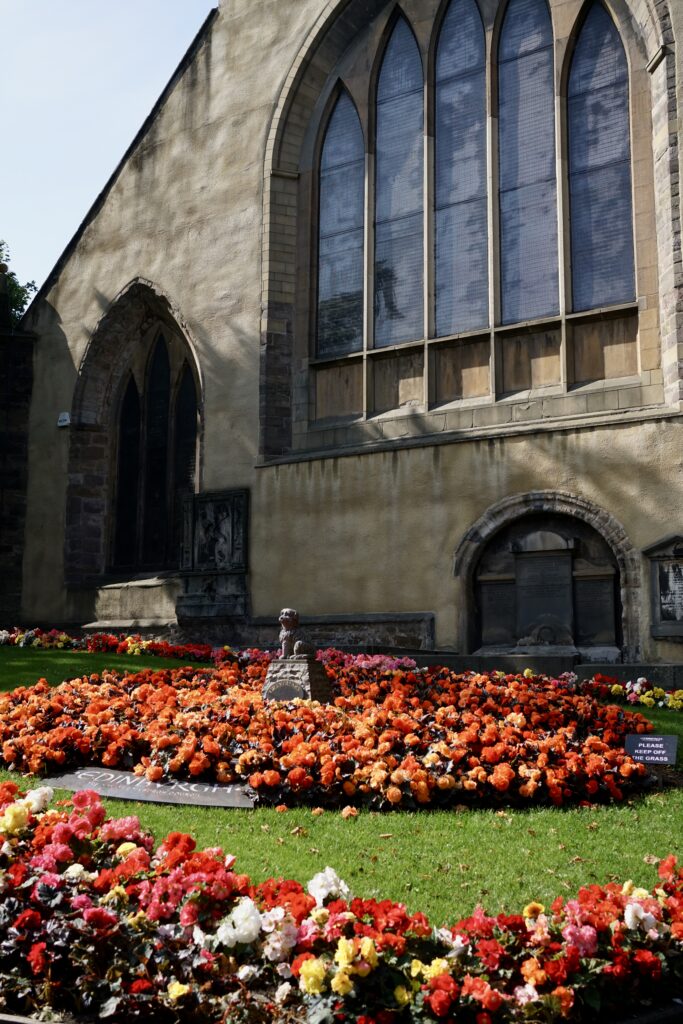 A statue of Bobby the dog surrounded by flowers in Greyfriars Kirk