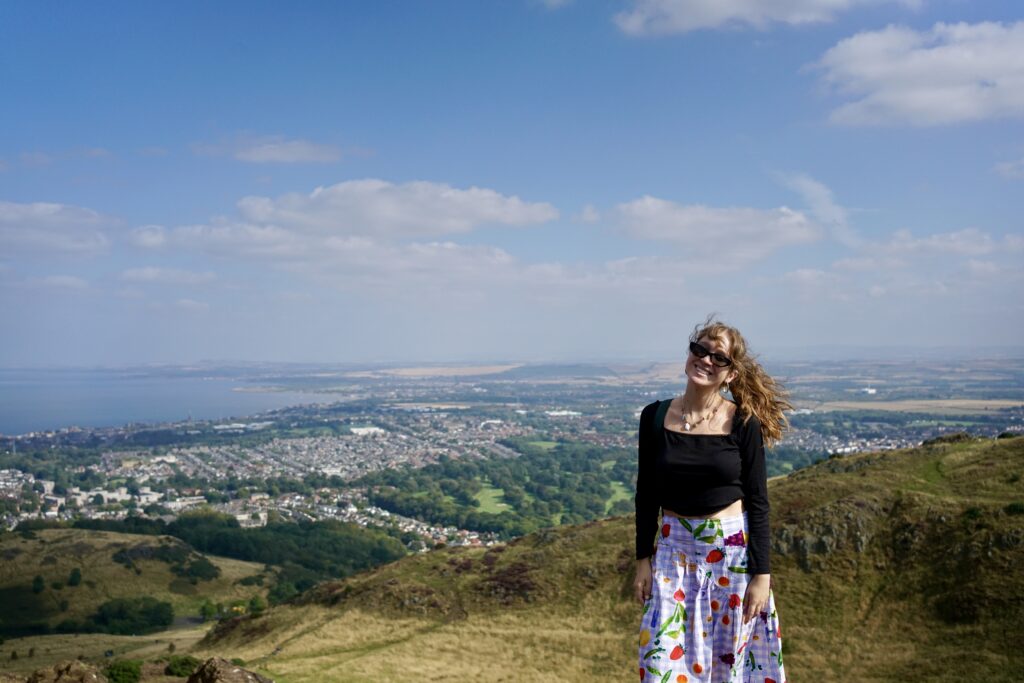 A woman posing with the view of Arthur's Seat