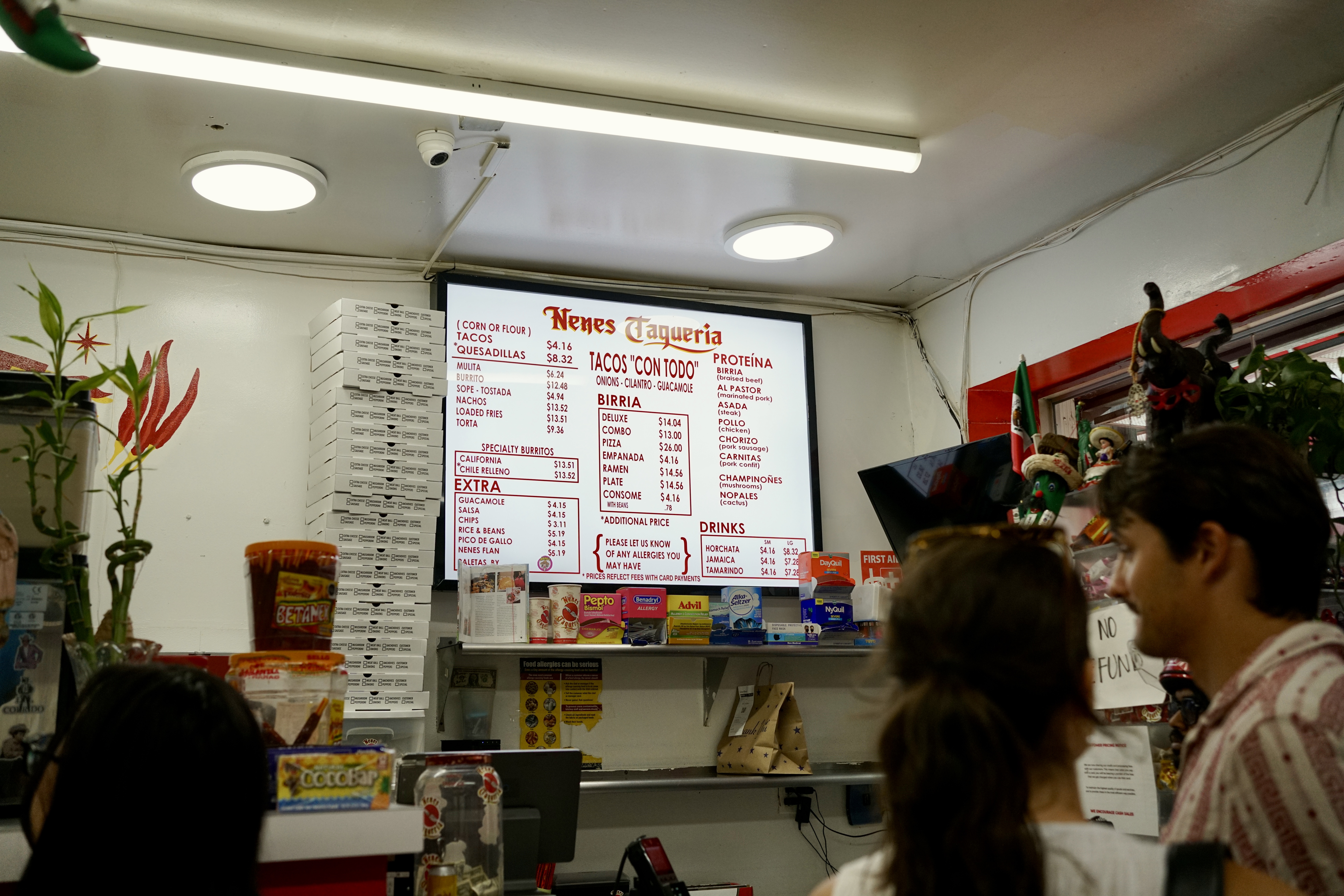 the counter at Nene's Deli Taqueria with the menu sign lit up
