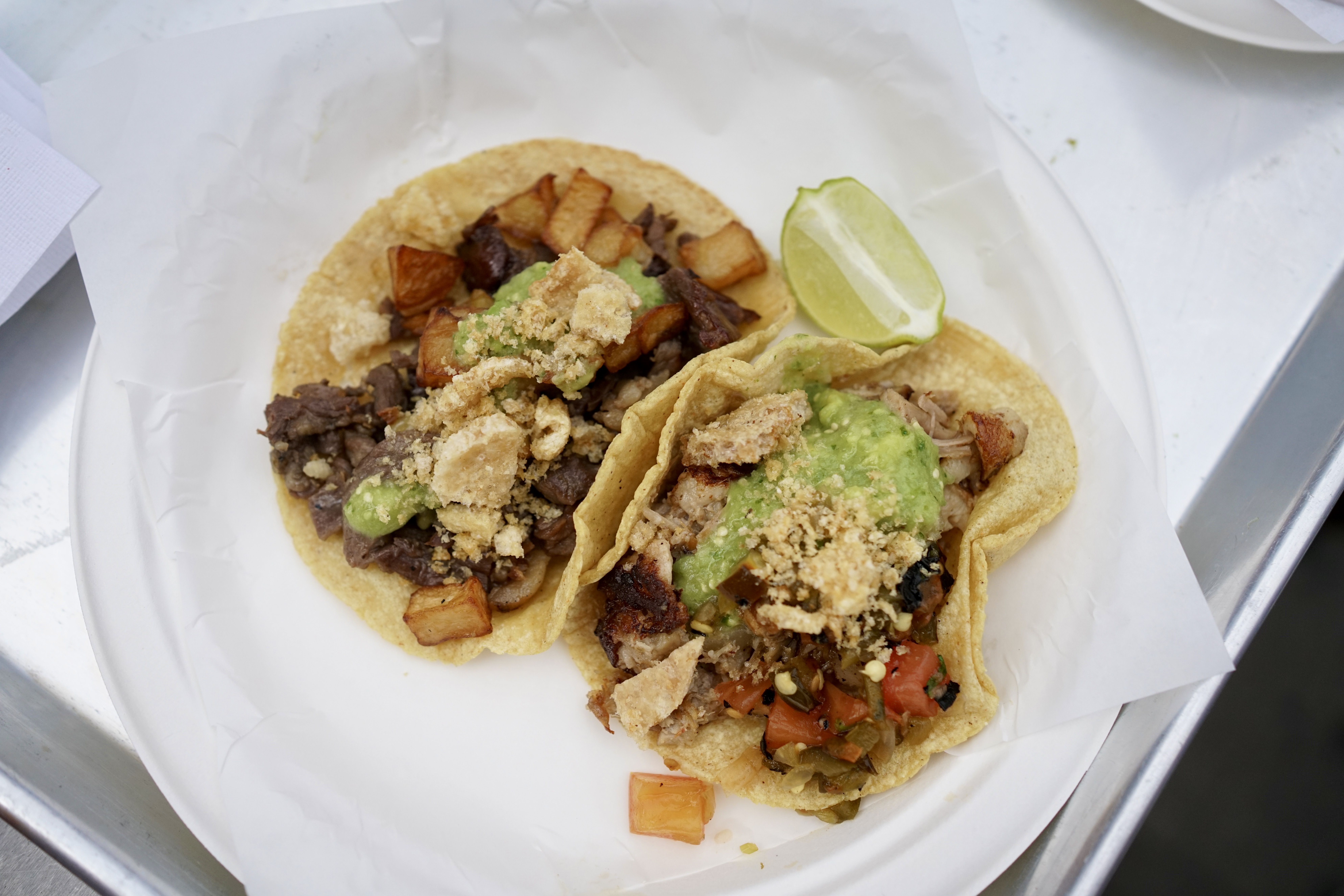 Two tacos with lime on a plate