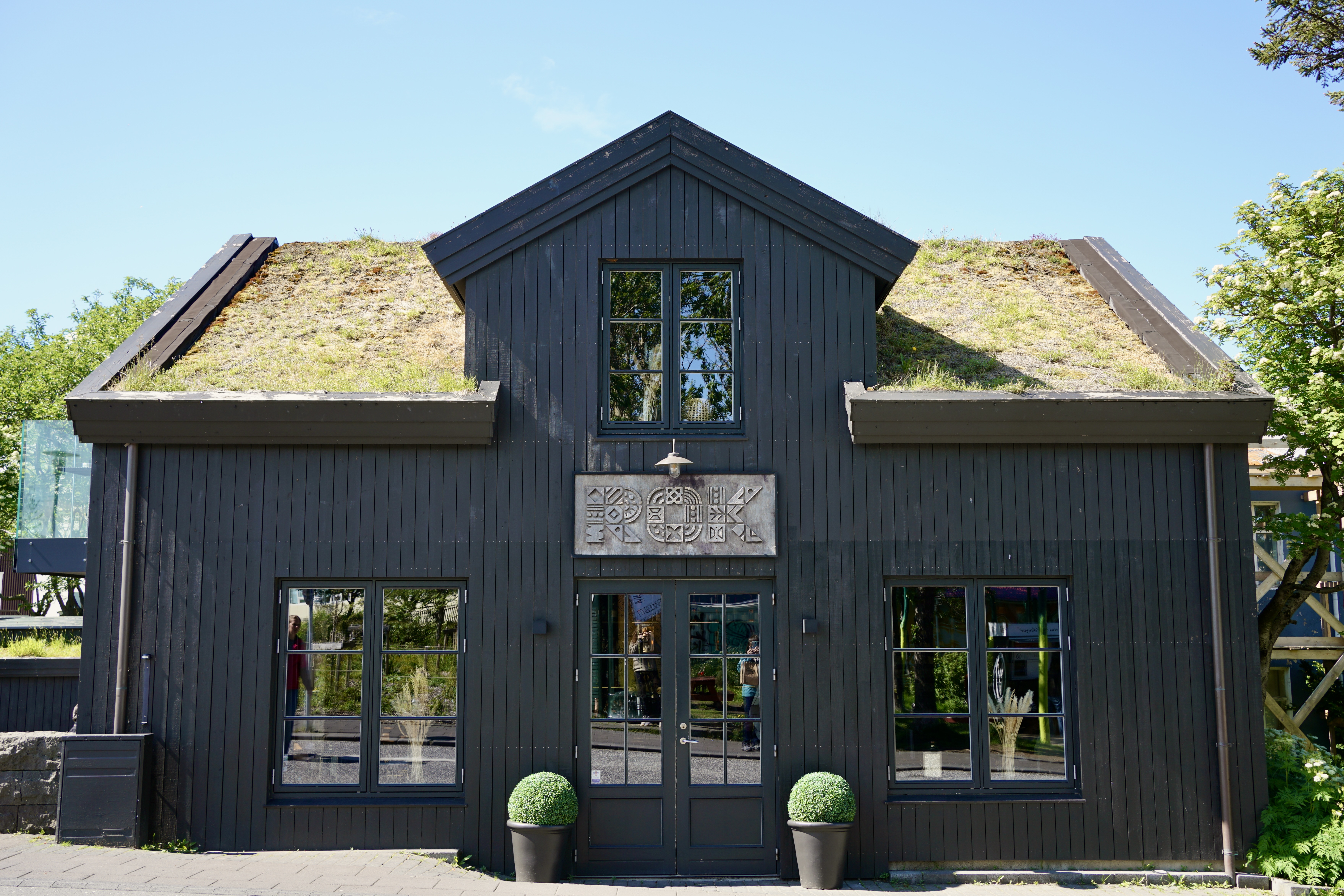 Exterior of a black restaurant with a grass roof