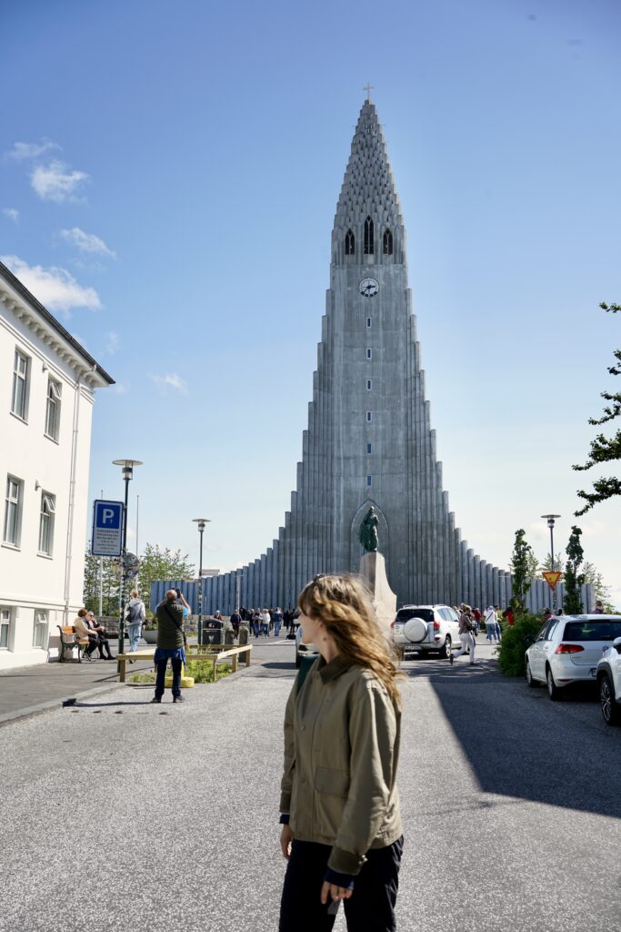 A woman stands in front of Hallgrimskirkja on a sunny day