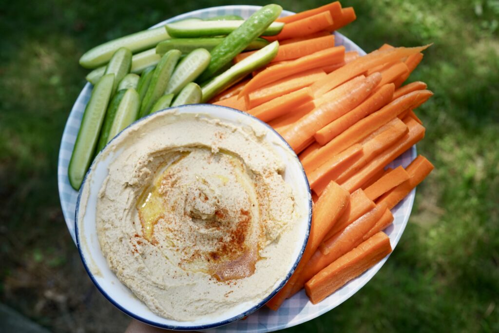 hummus on a plate with carrots and cucumbers
