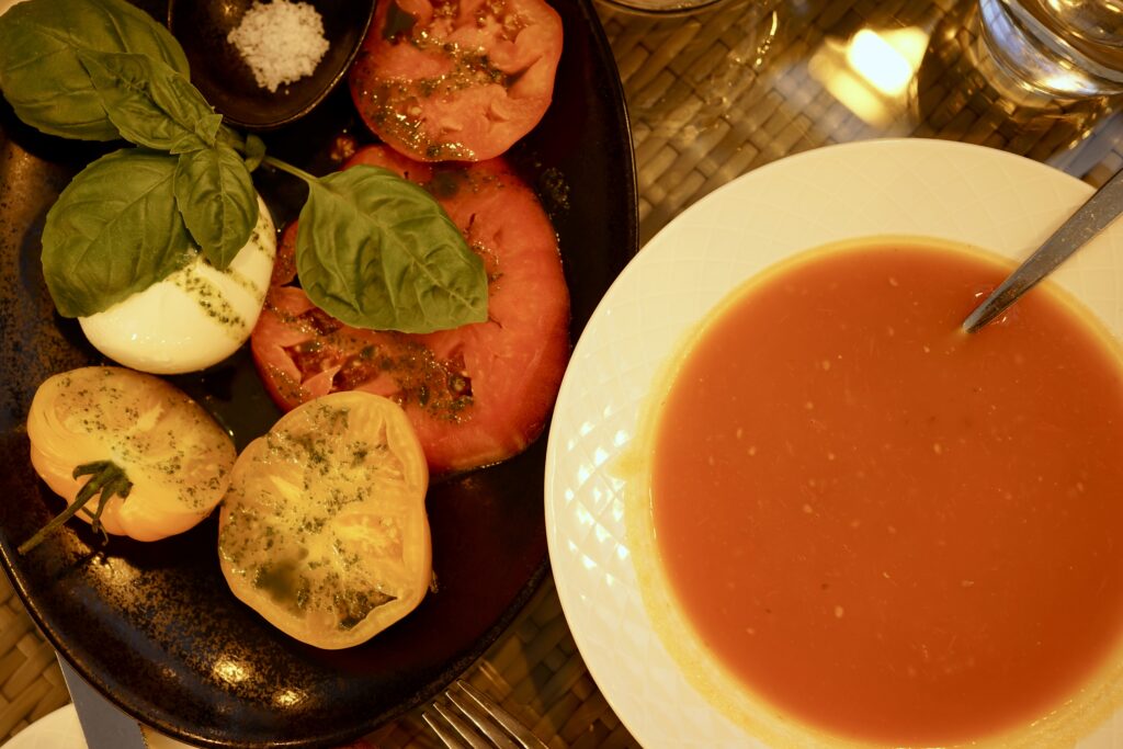 A plate of tomatoes next to tomato soup