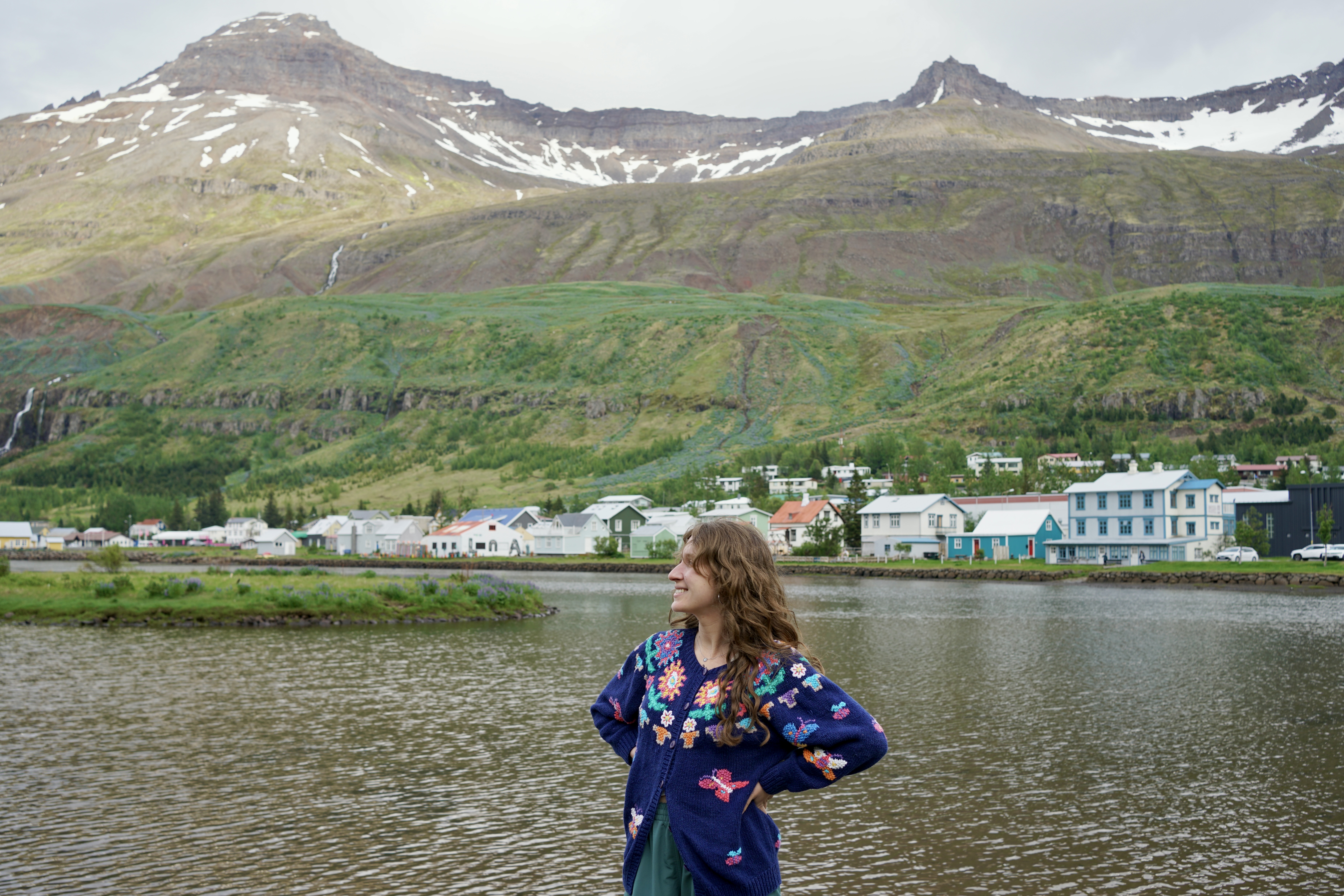 A woman poses with the picturesque Seydisfjordur behind her