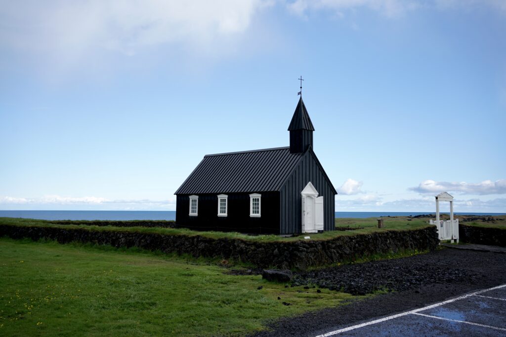 A black church in Iceland against the blue sky and green grass