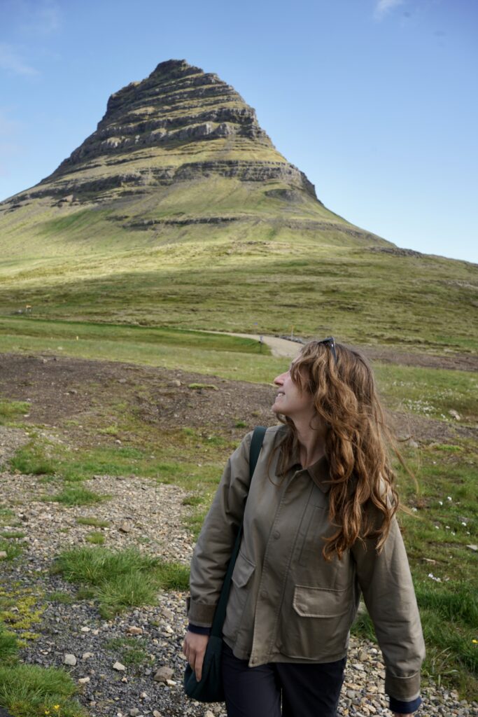 A woman looks back at the Kirkjufell mountain