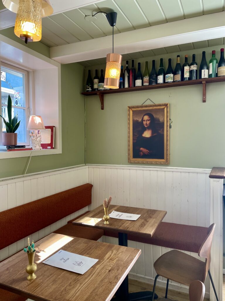 The interior of a wine bar with bottles on the wall and a painting of Mona Lisa