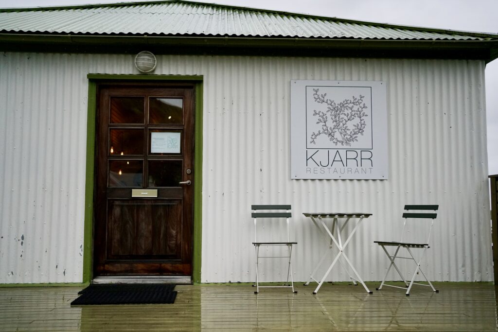 The exterior of a restaurant with a table and two chairs outside