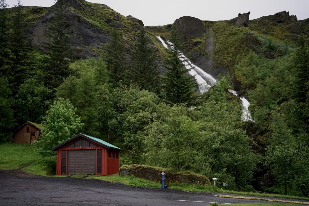 View of a waterfall on a ridge and a red house