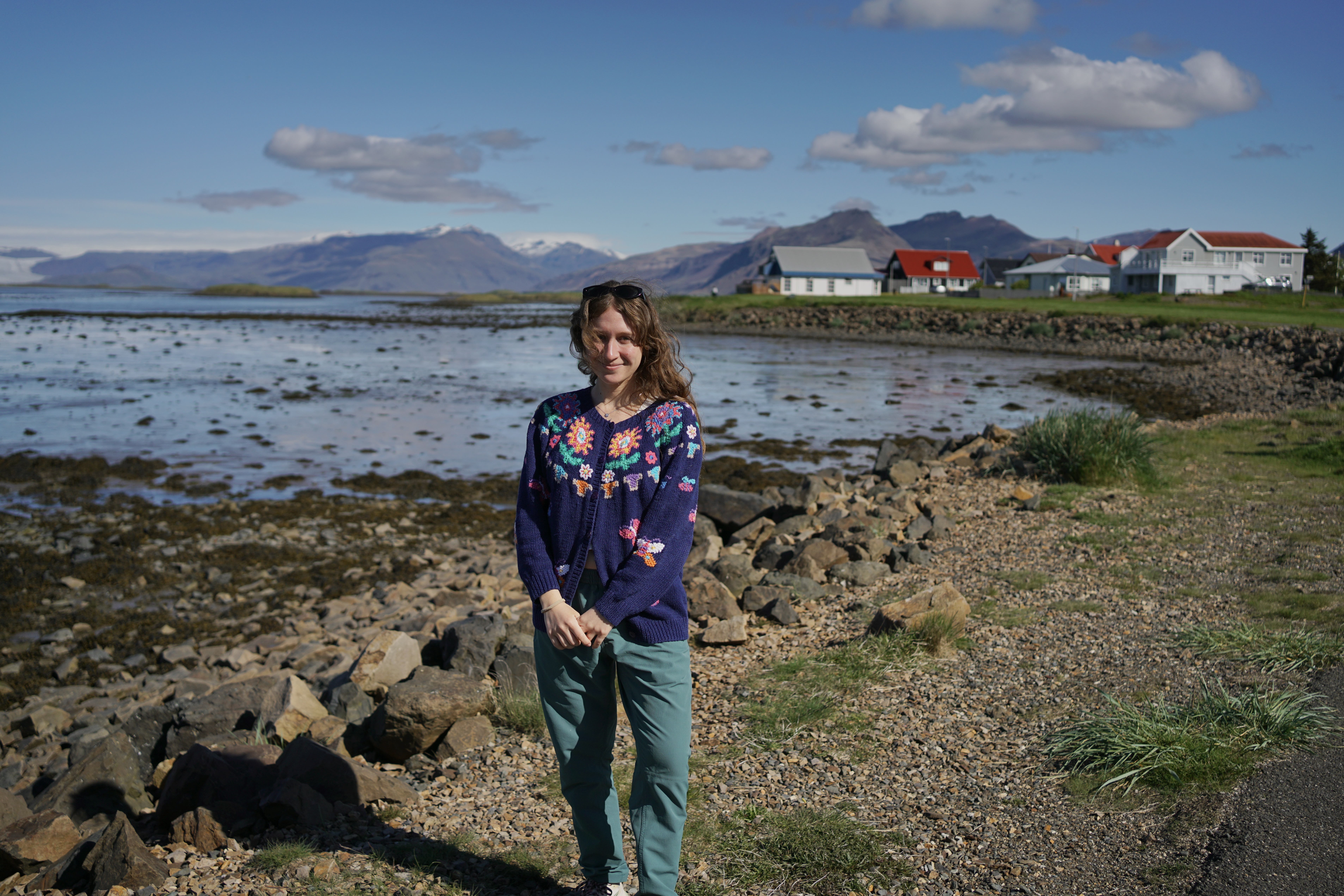 A woman stands in front of a vista on the water in Iceland