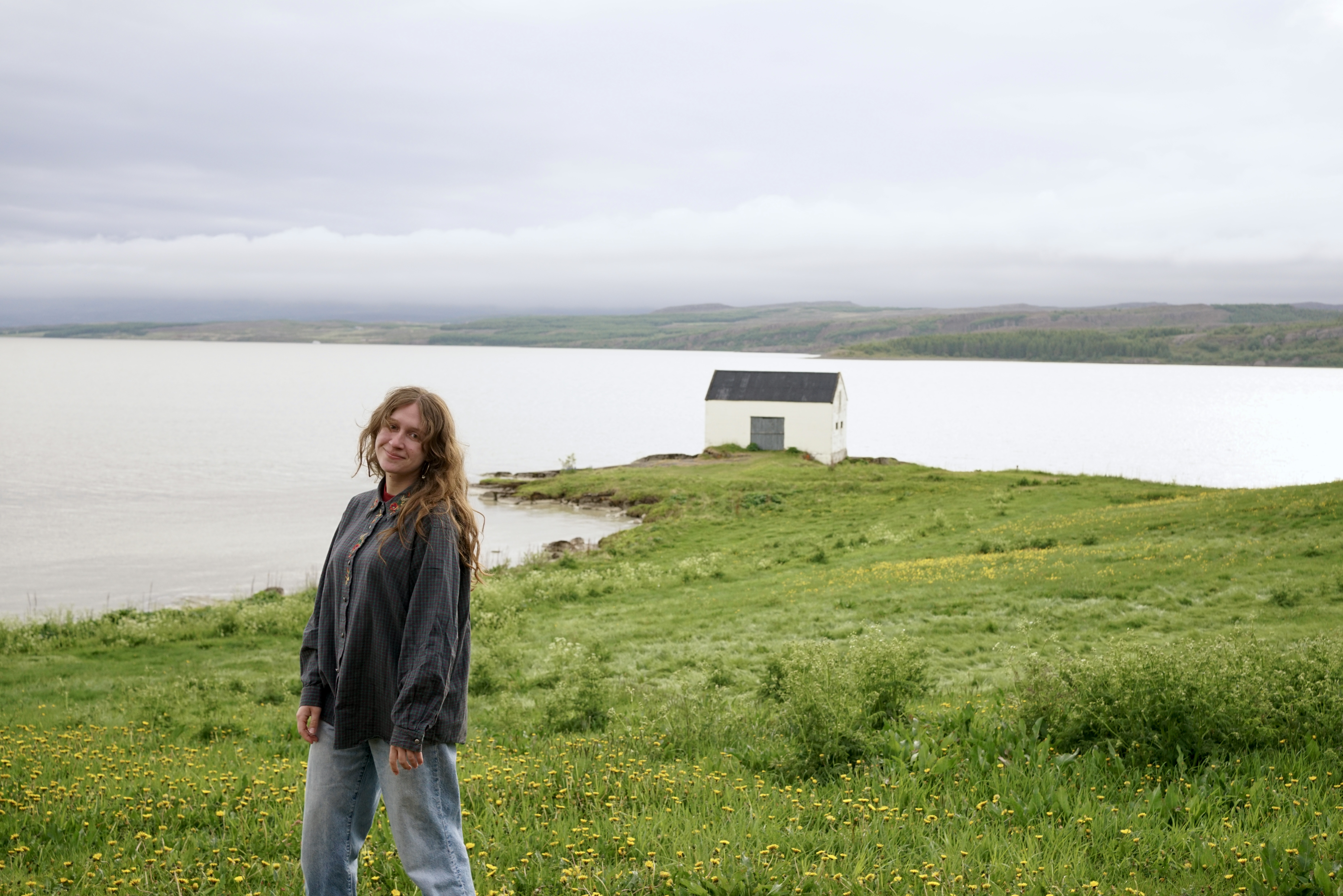 A woman stands in front of a house on a lake