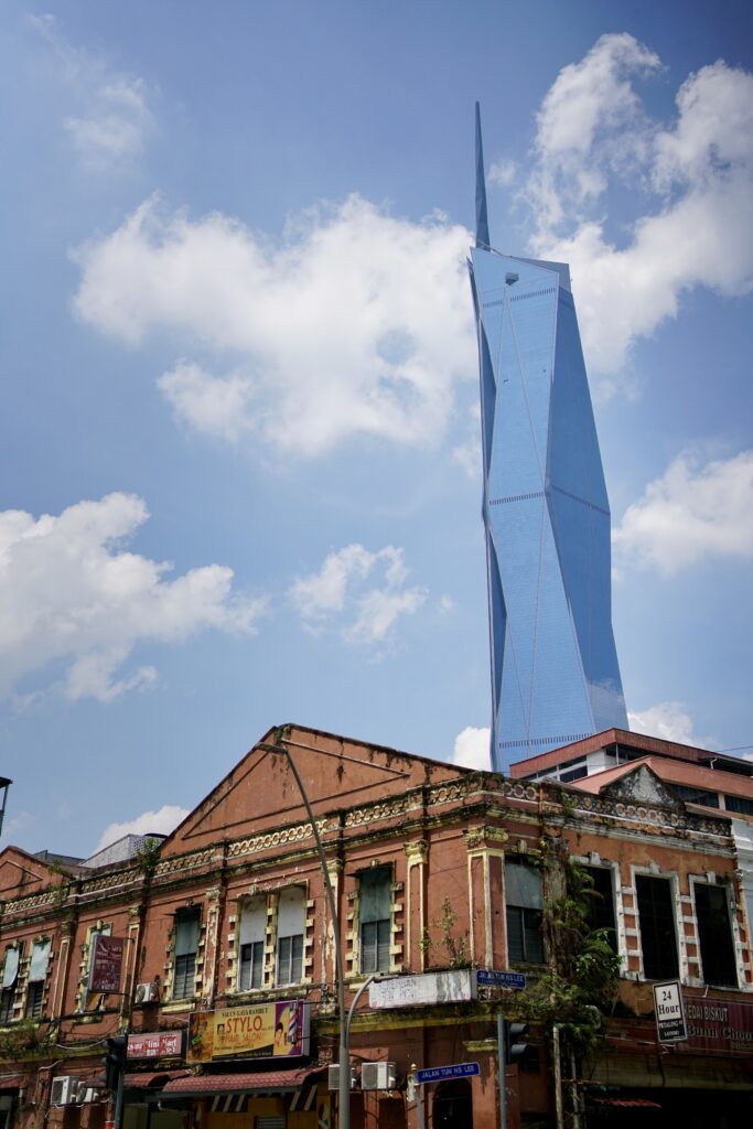 An older red building is juxtaposed by Merdeka 118, the tallest building in Kuala Lumpur