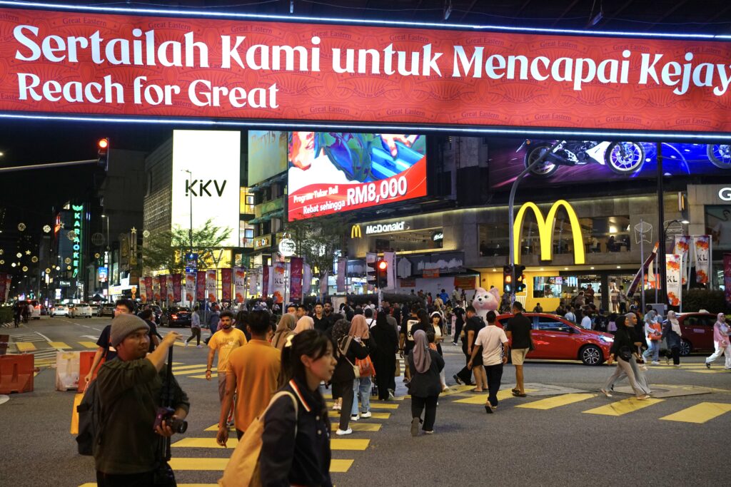 the busy crosswalk in bukit bintang with illuminated billboards at night