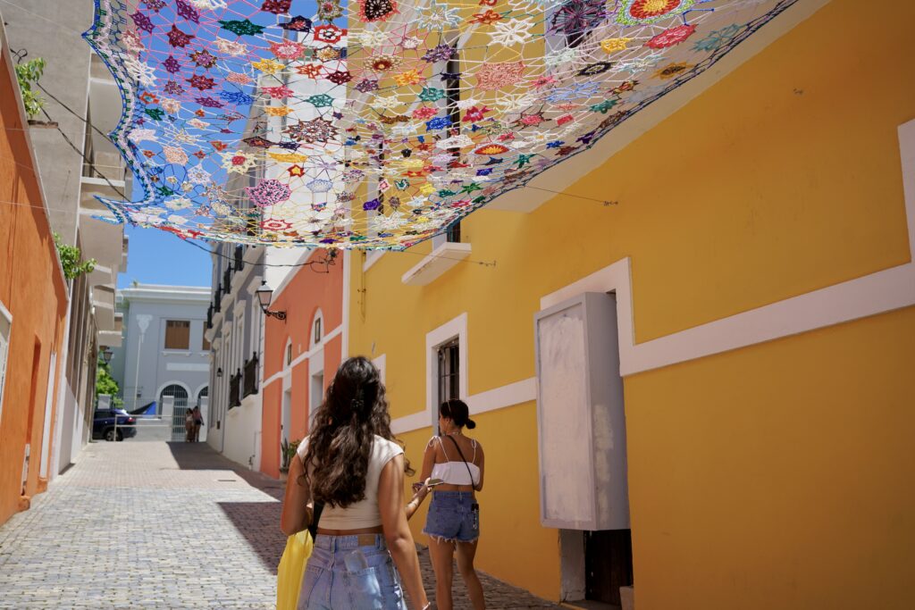Two girls walking under crochet art in San Juan, Puerto Rico
