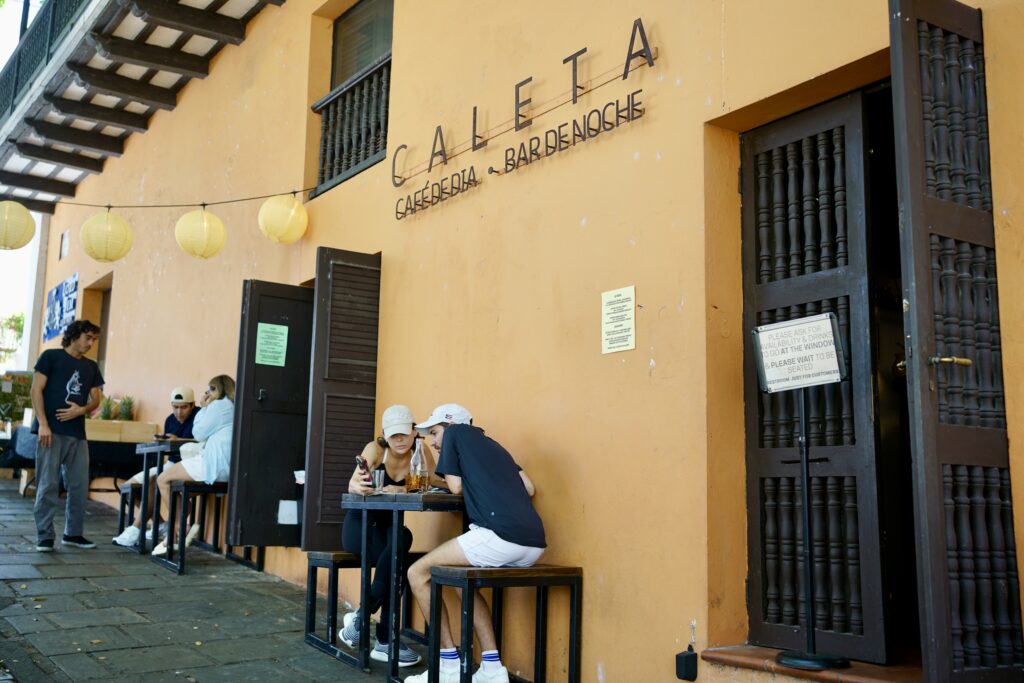 The exterior of a cafe with a couple sitting at a table out front