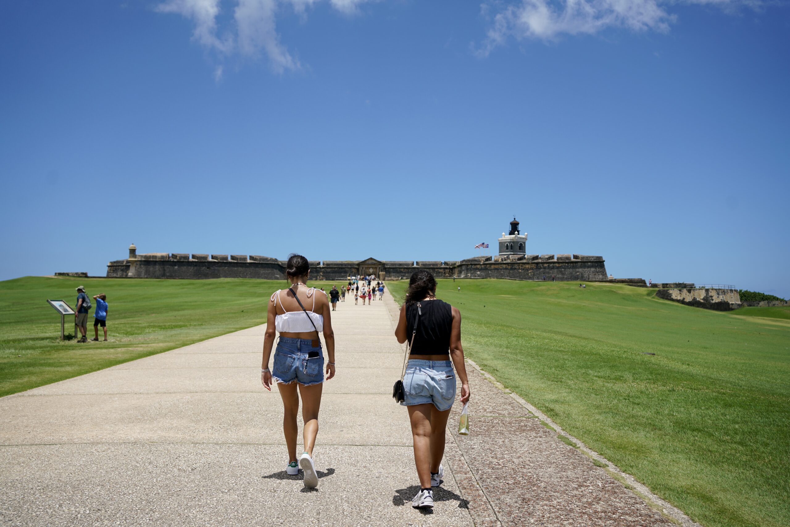two women walk towards el morro in san juan