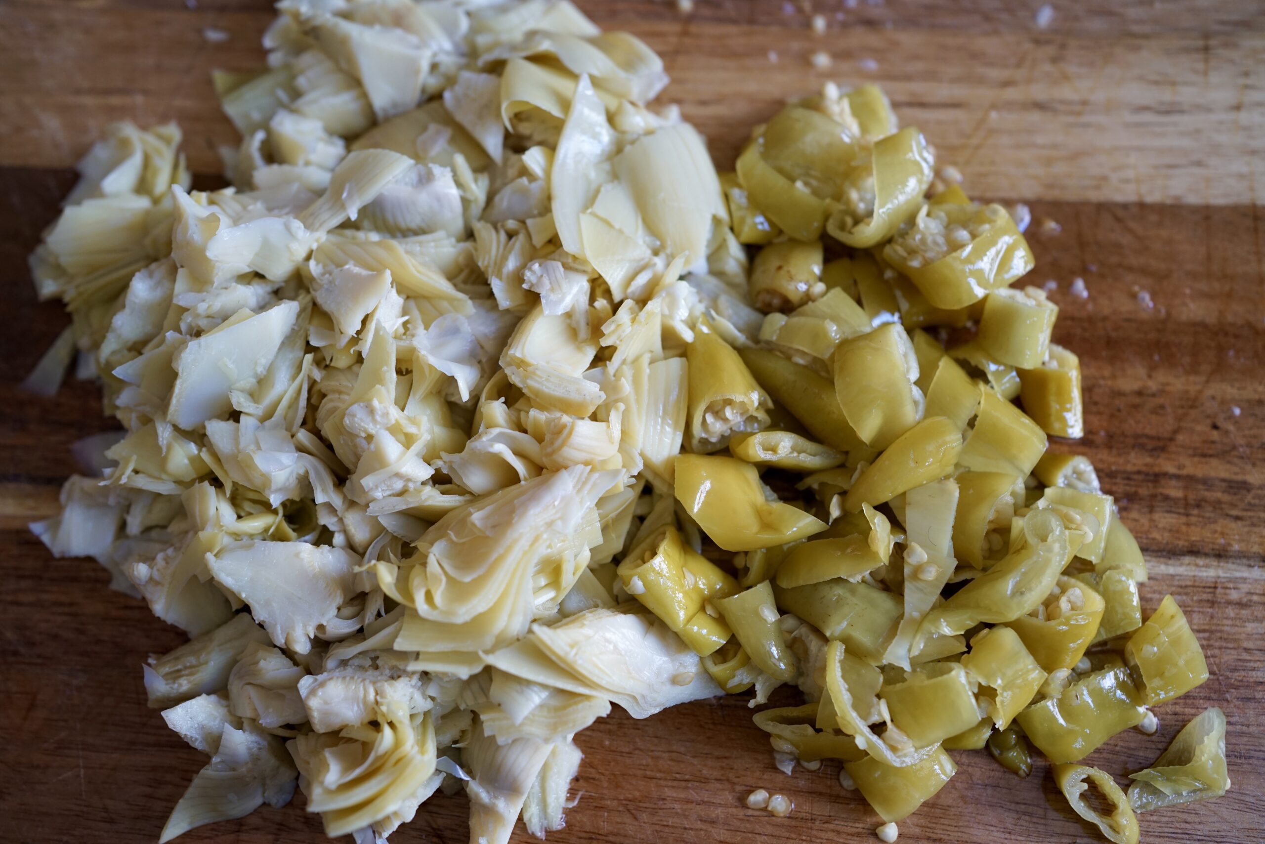 chopped artichoke and pepperoncini on a cutting board