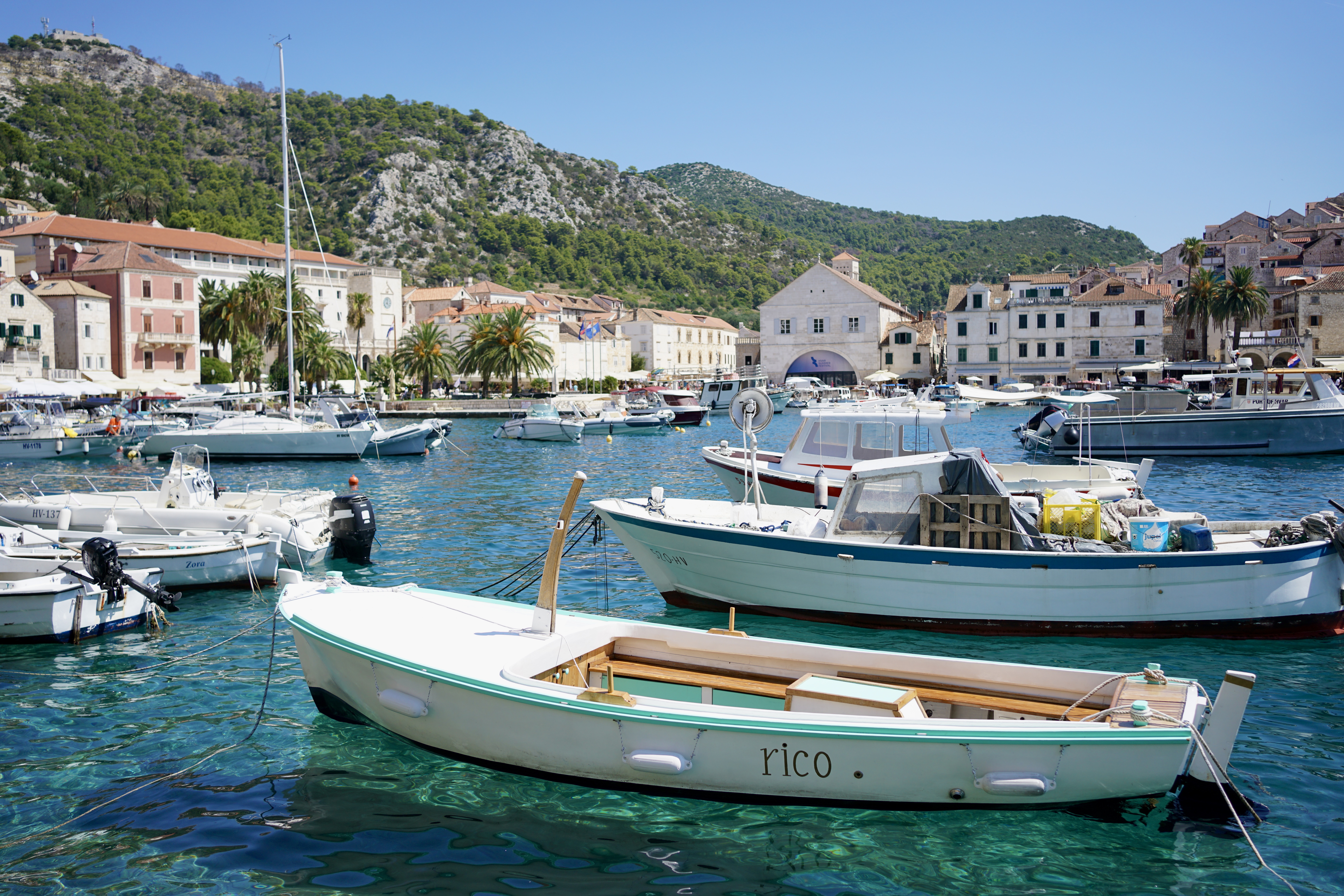 Small boats in Hvar's harbor floating in crystal blue water