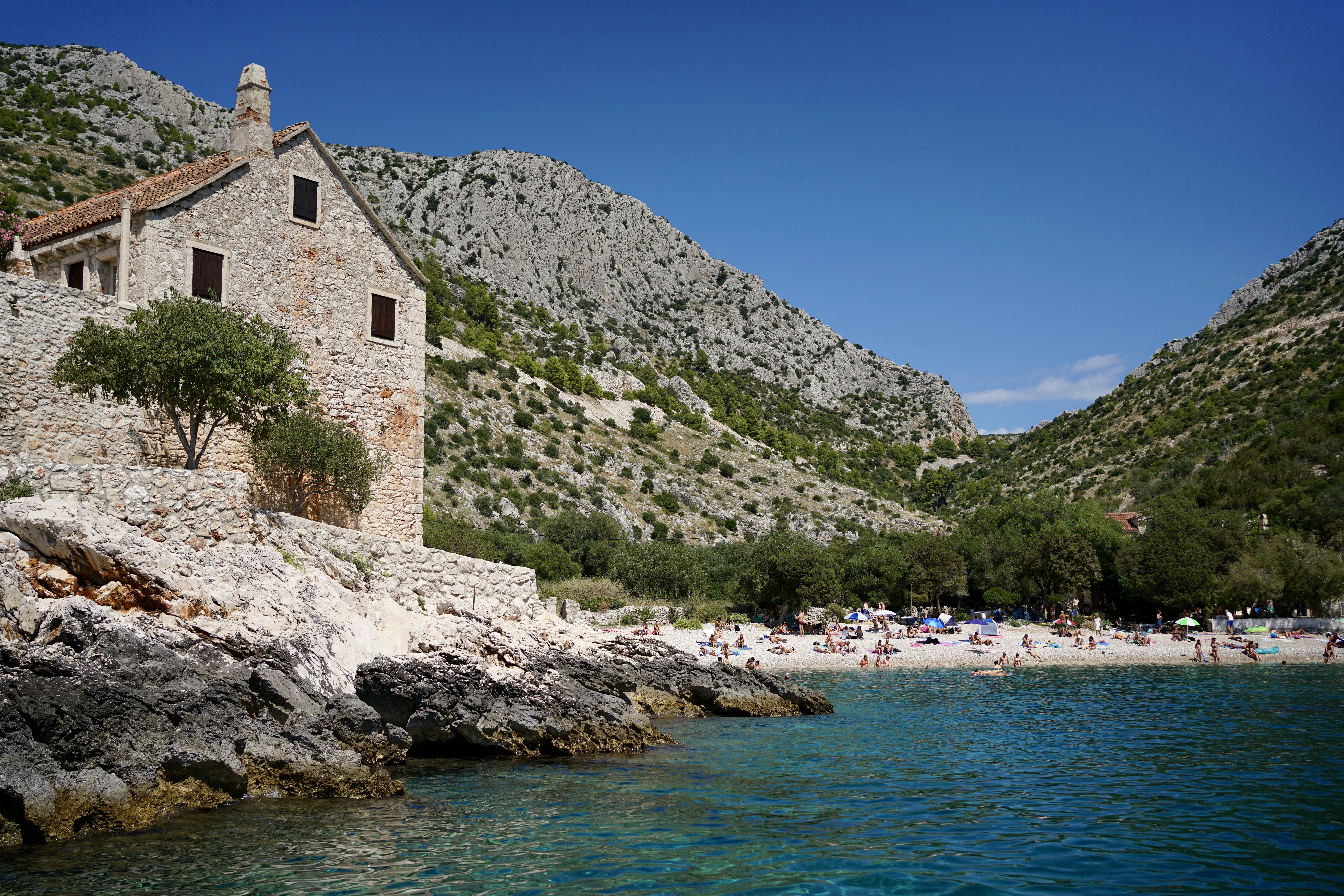 a beach in hvar with a building on the coast