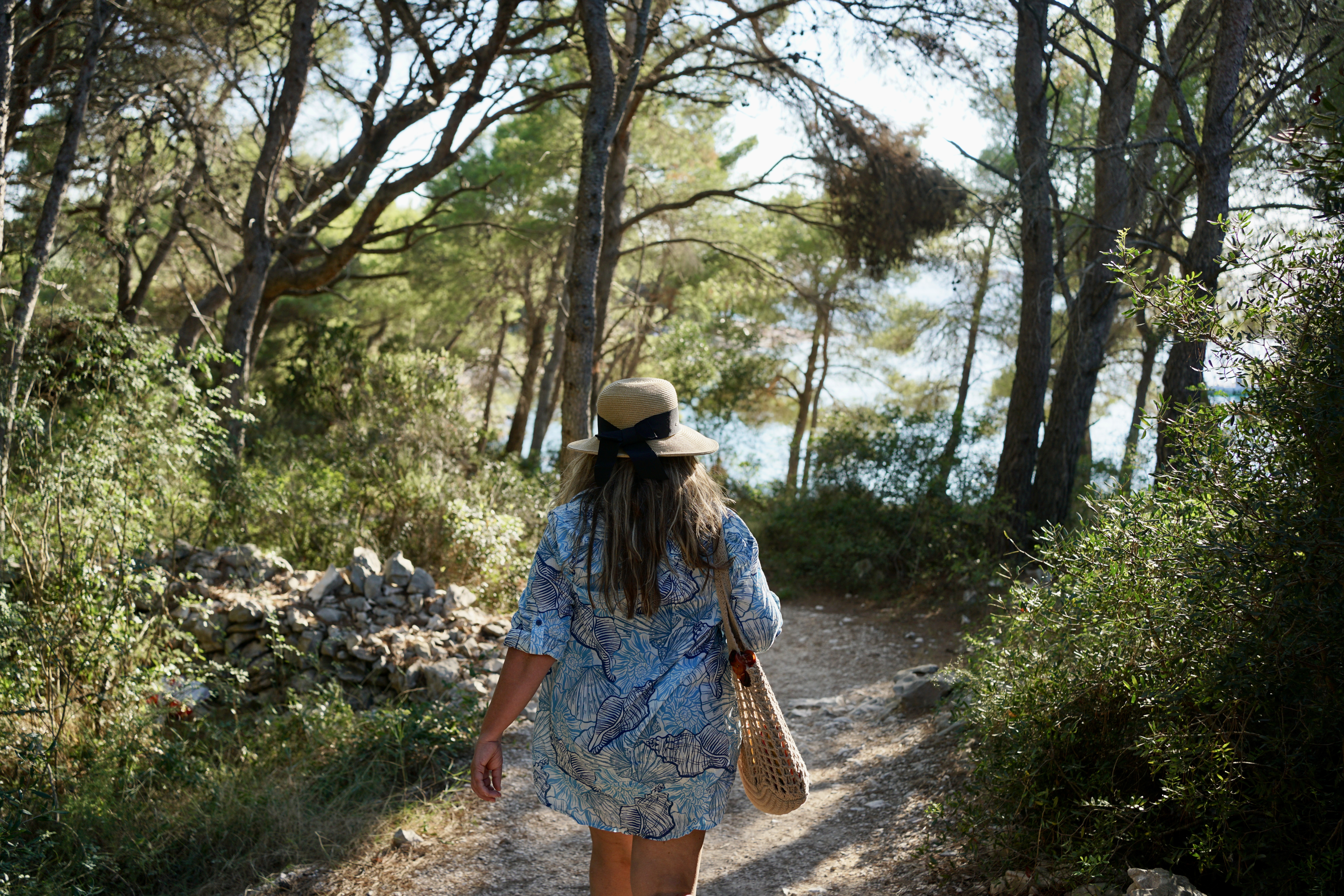 A woman in a hat walks around a small island