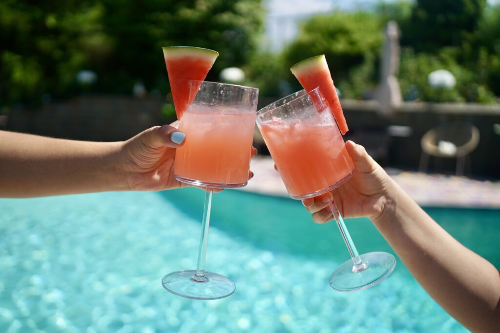 two watermelon margaritas doing a cheers by a pool